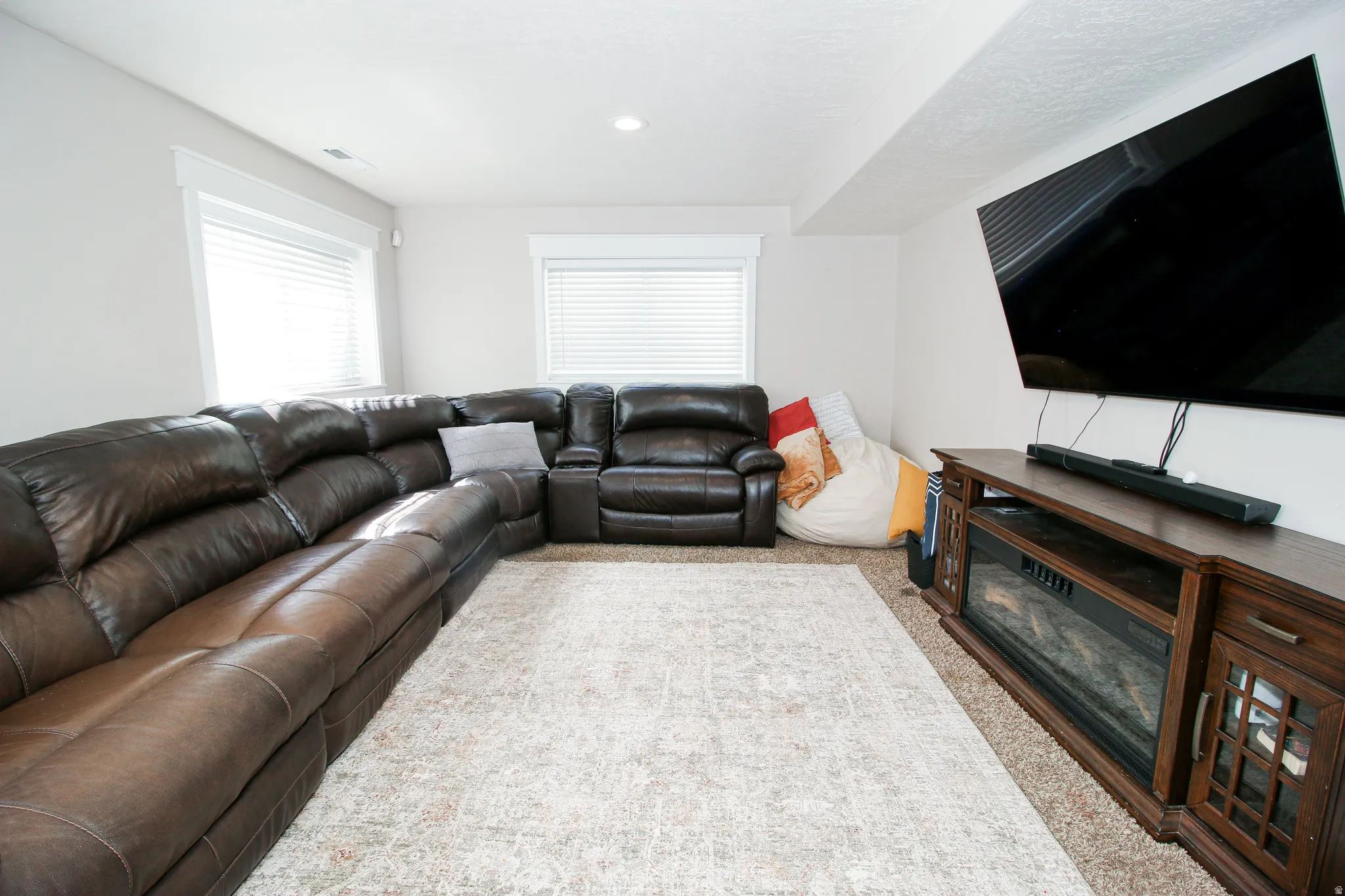 Carpeted living area featuring recessed lighting and two windows with blinds