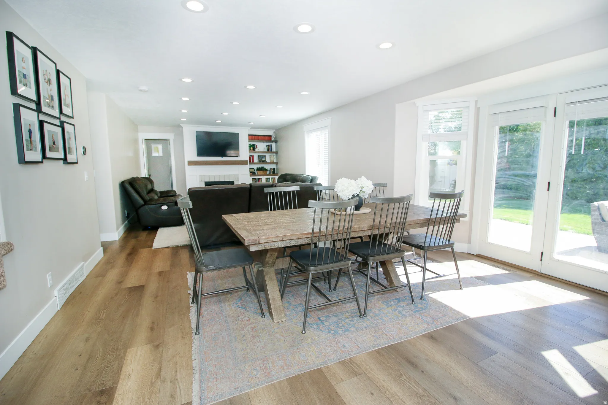 Bright dining area with wood-finish flooring, recessed lighting, and direct access to an outdoor patio through French doors