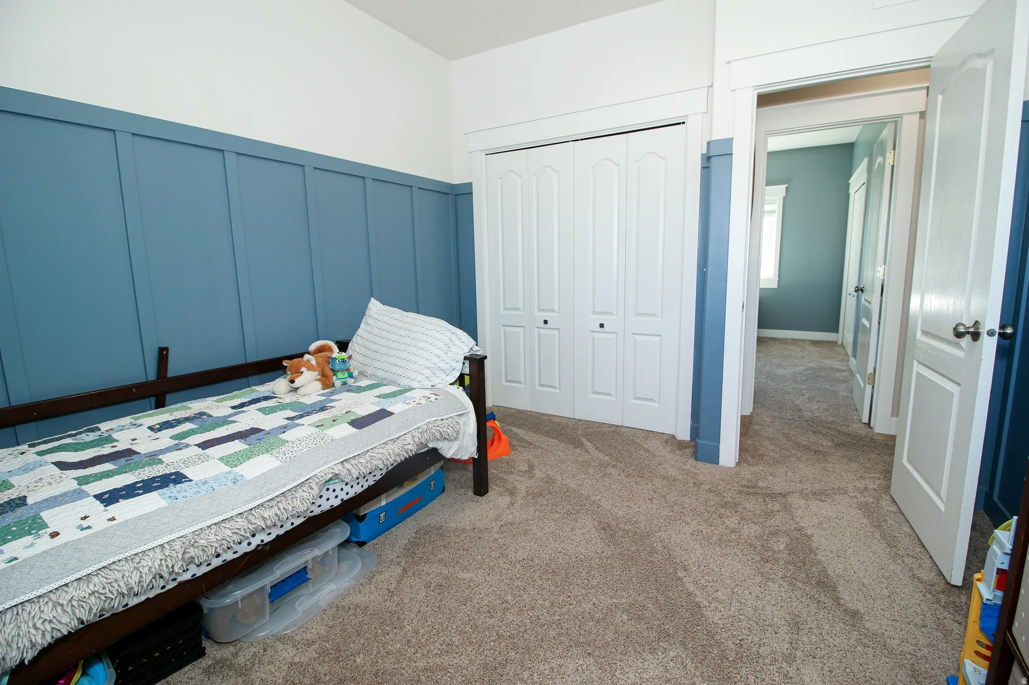 Bedroom featuring wainscoting accent wall, neutral carpeting, and a bi-fold closet