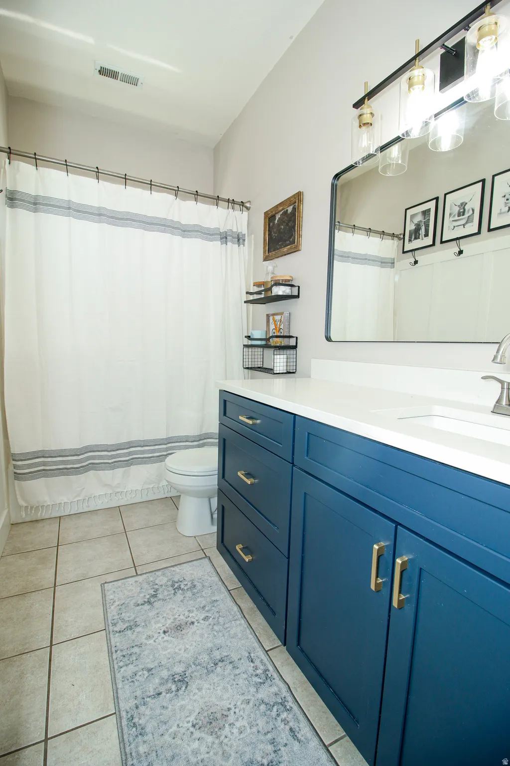 Bathroom featuring a single vanity with a white countertop, blue cabinetry, and a rectangular mirror