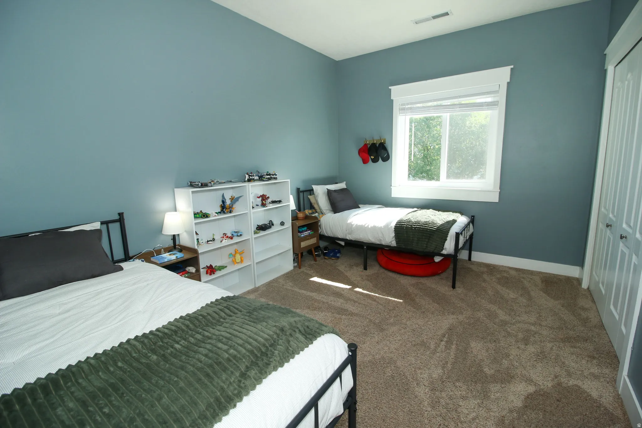 Carpeted room featuring a window with white trim, a double-door closet, and painted walls