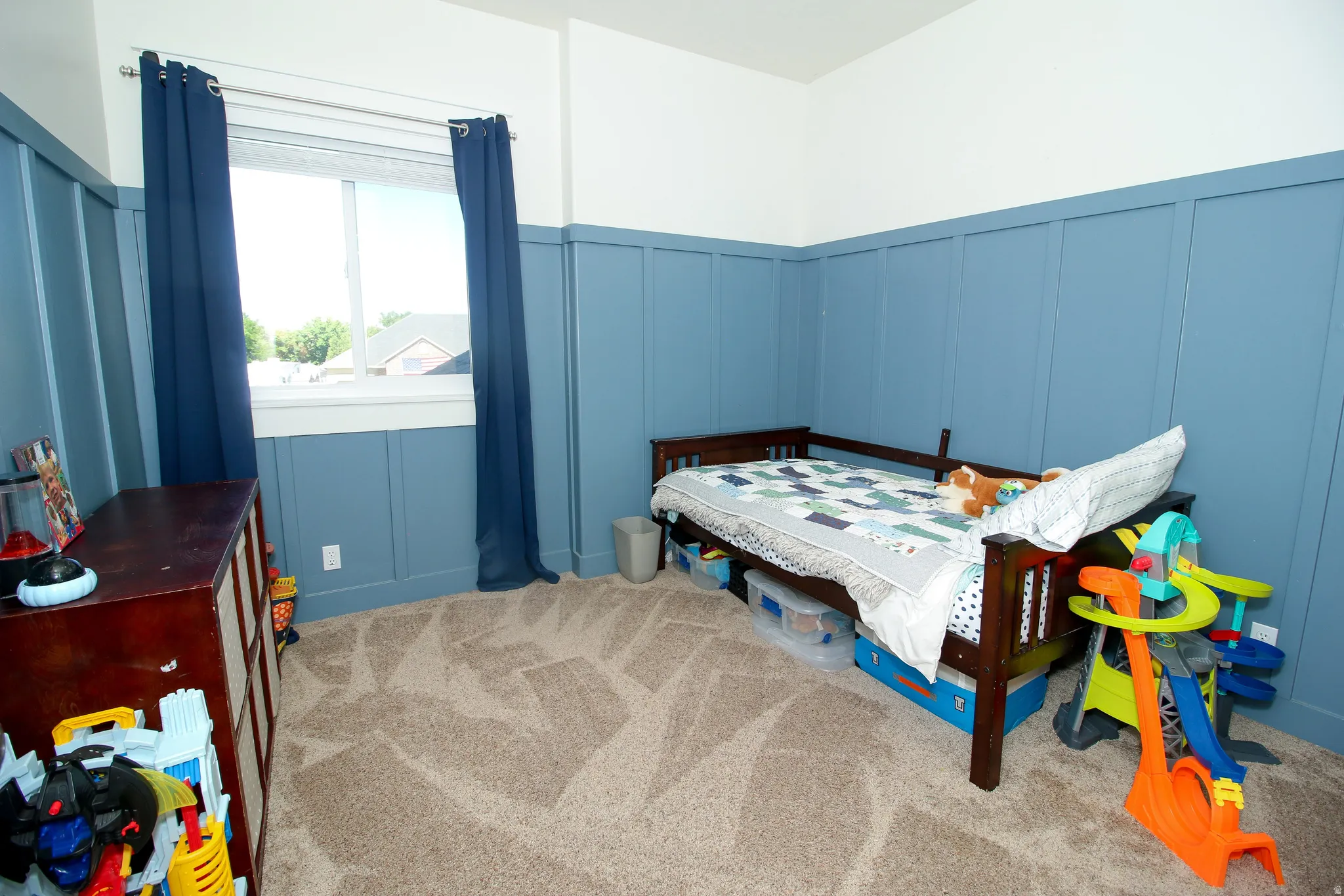 Room featuring board and batten wall treatment, neutral-toned carpet, and a large window with white trim