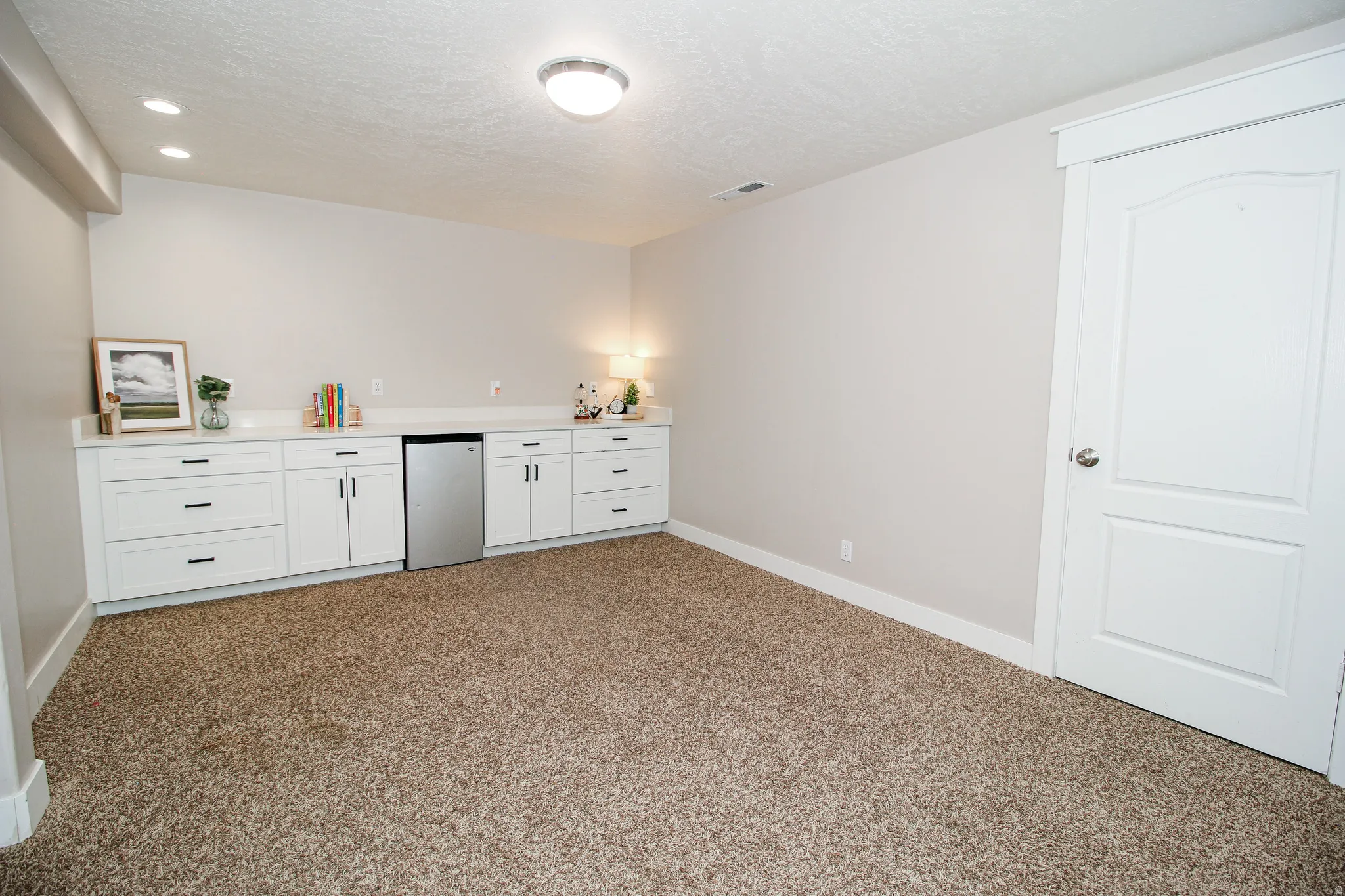 Built-in white cabinetry with dark hardware and a stainless-steel beverage refrigerator