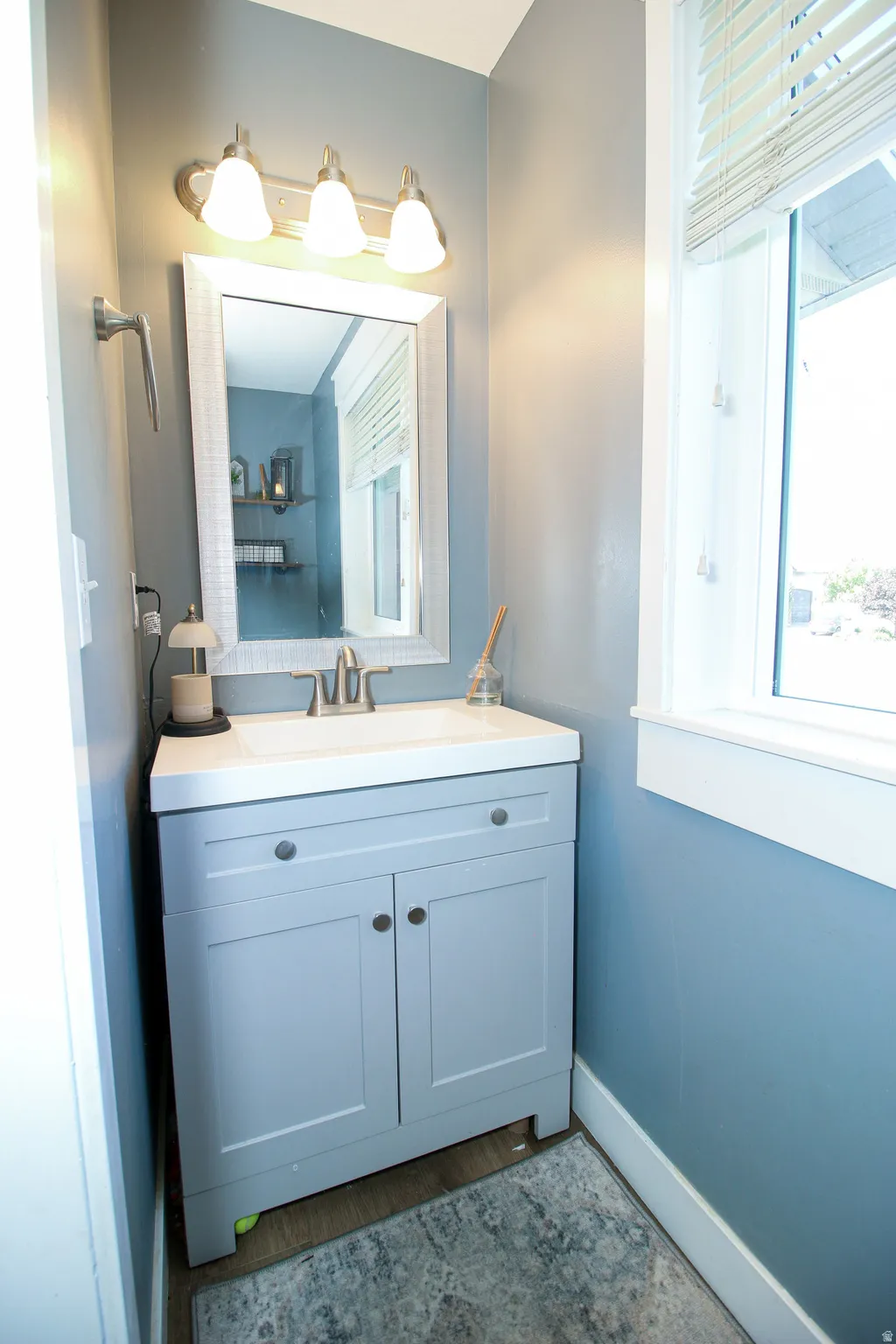 Powder room featuring a single-sink vanity with light blue cabinetry, white countertop, and brushed nickel faucet