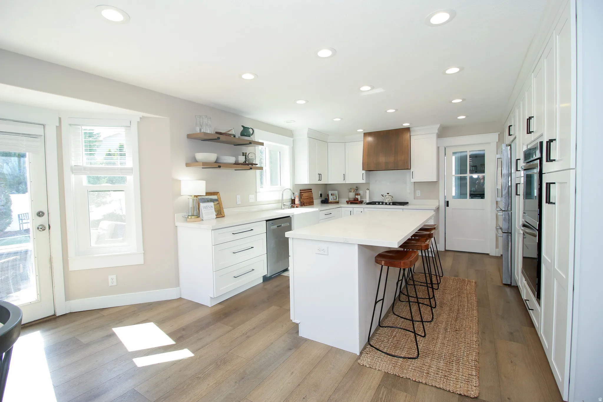 Spacious kitchen featuring white cabinetry, light wood-finish flooring, recessed lighting, and a kitchen island with seating