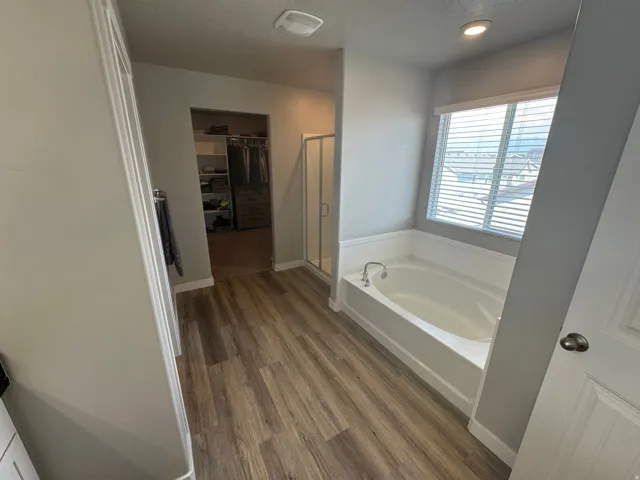 Bathroom featuring an integrated soaking tub with white wainscoting and a window with blinds