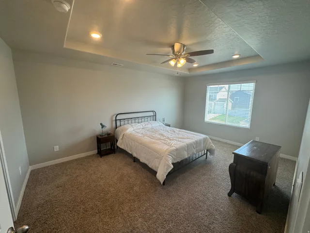 Carpeted room with a tray ceiling featuring recessed lighting and a ceiling fan