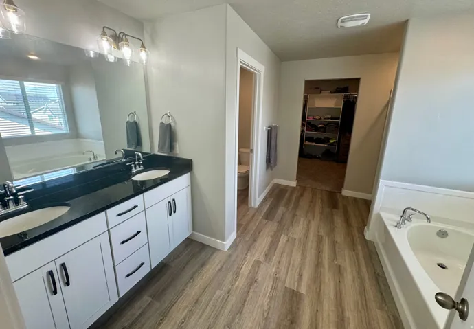 Dual vanity featuring white cabinetry, black countertops, and undermount sinks