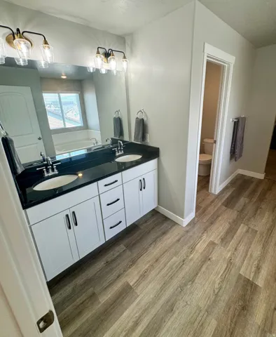 Dual vanity featuring a black countertop and white cabinetry with black hardware
