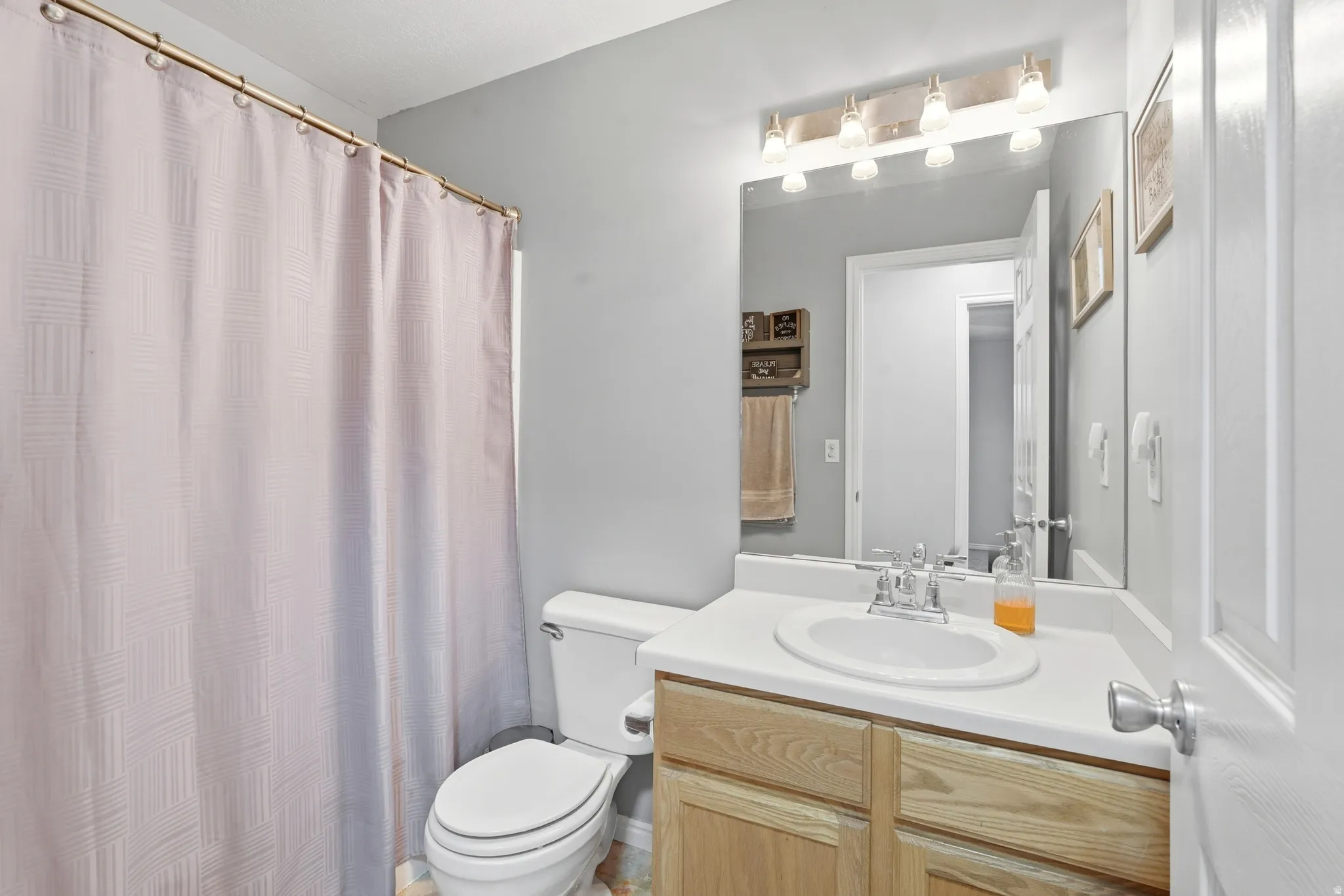Bathroom featuring a wood-finish vanity with an integrated sink and a white countertop