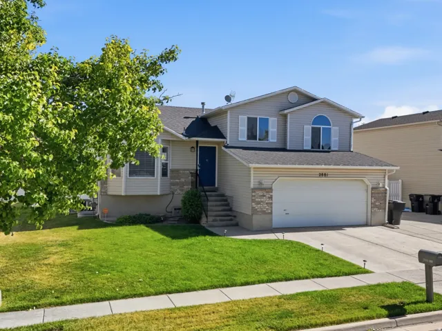 Two-story residence featuring a two-car garage, stone accents, and a vibrant green lawn