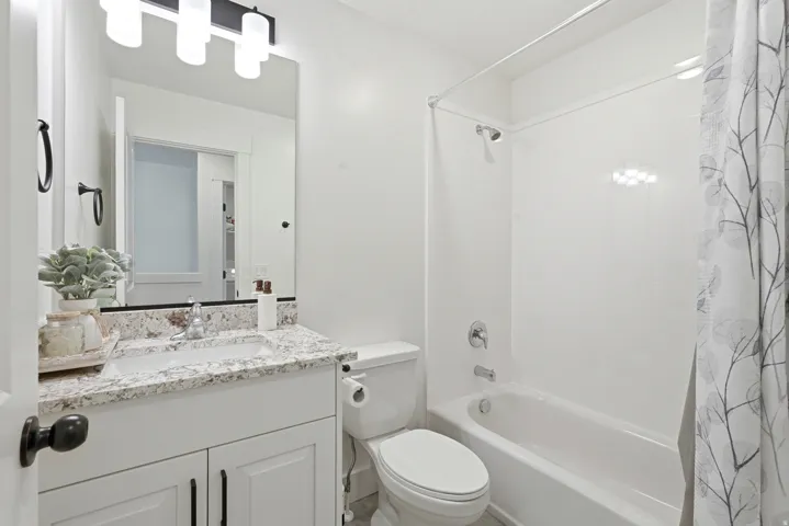 Bathroom featuring a white vanity with a speckled countertop and an undermount sink