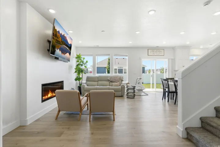Open-concept living space with wood-finish flooring, recessed lighting, and a modern linear fireplace
