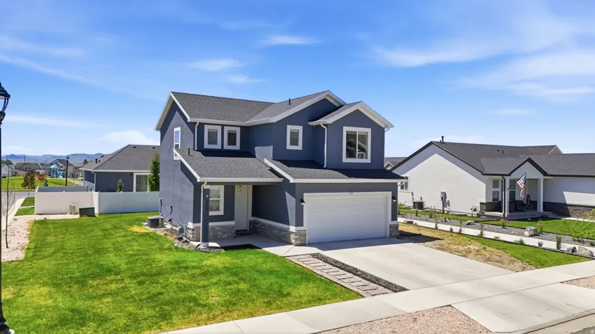 Two-story residence featuring a dark gray exterior with white trim, a two-car garage, concrete driveway, and a front lawn