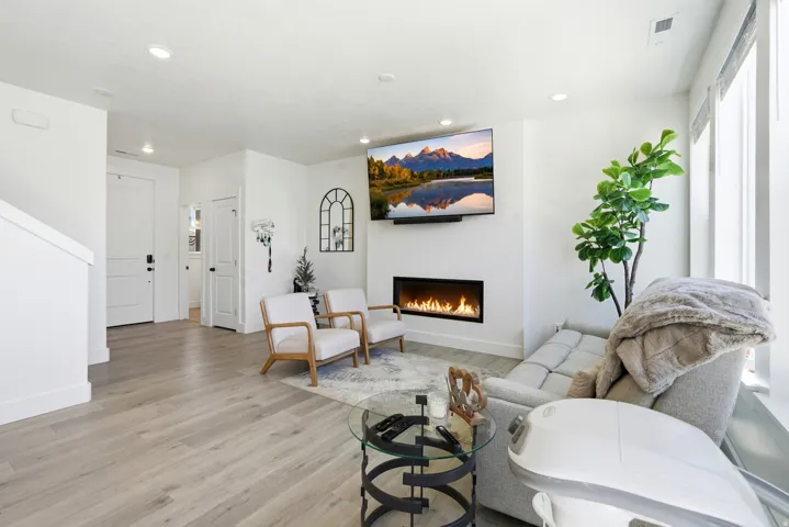 Open living space featuring wood-finish flooring, a linear electric fireplace, and recessed lighting