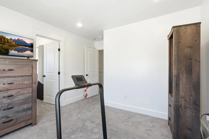 Carpeted interior space featuring white walls and a white door with black hardware
