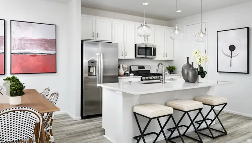 Contemporary kitchen featuring white cabinetry, stainless steel appliances, a center island with countertop seating, and light wood-finish flooring