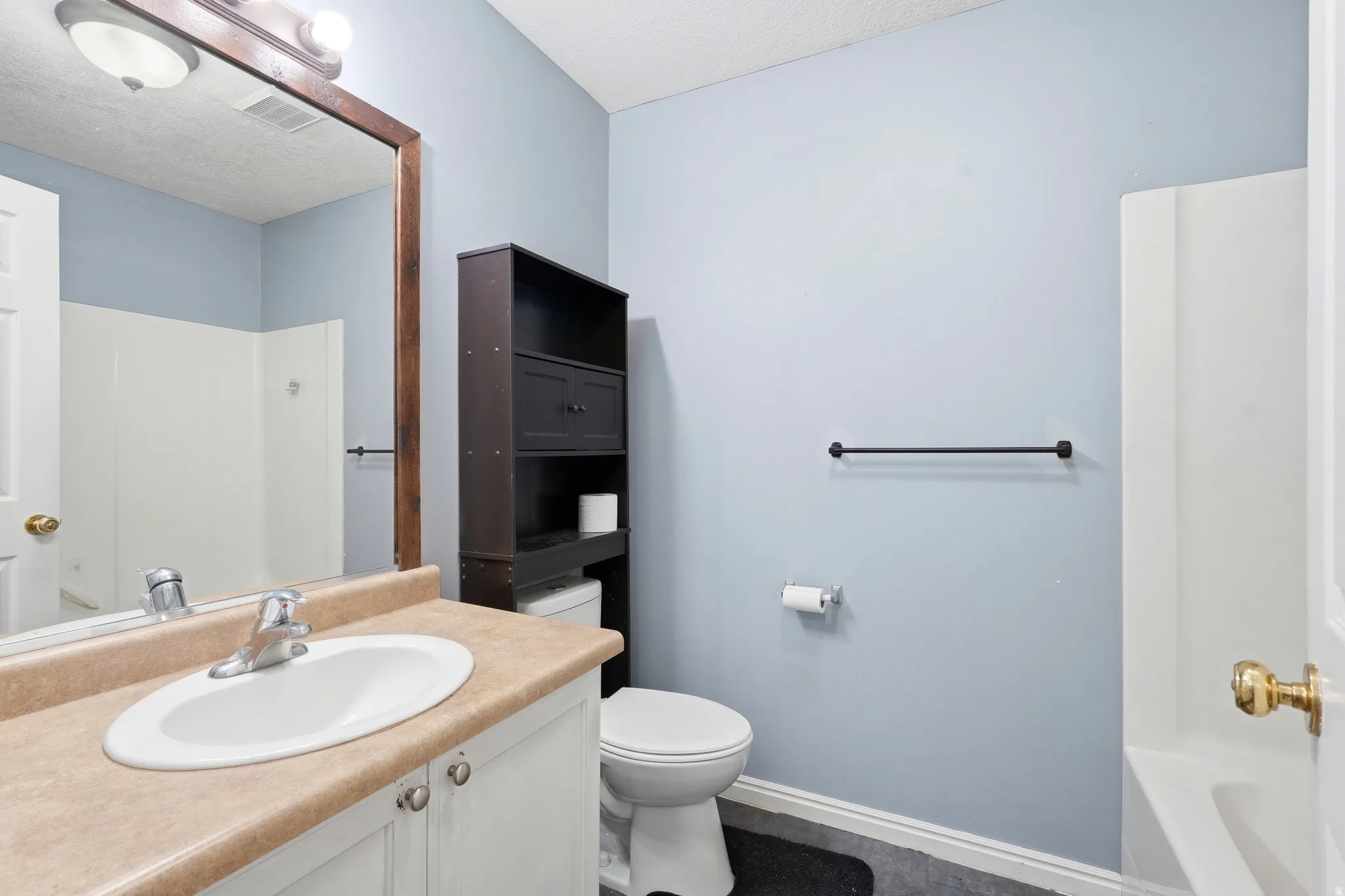 Bathroom featuring a white vanity with a tan countertop, an oval undermount sink, and a chrome faucet