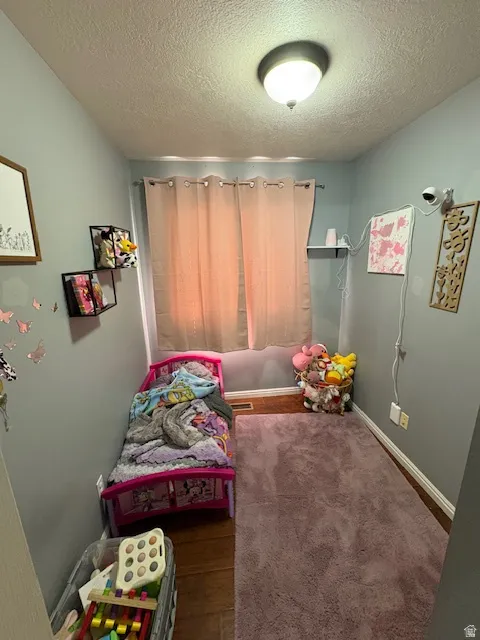 Room featuring wood-finish flooring, light blue wall paint, and a window with light-colored curtains