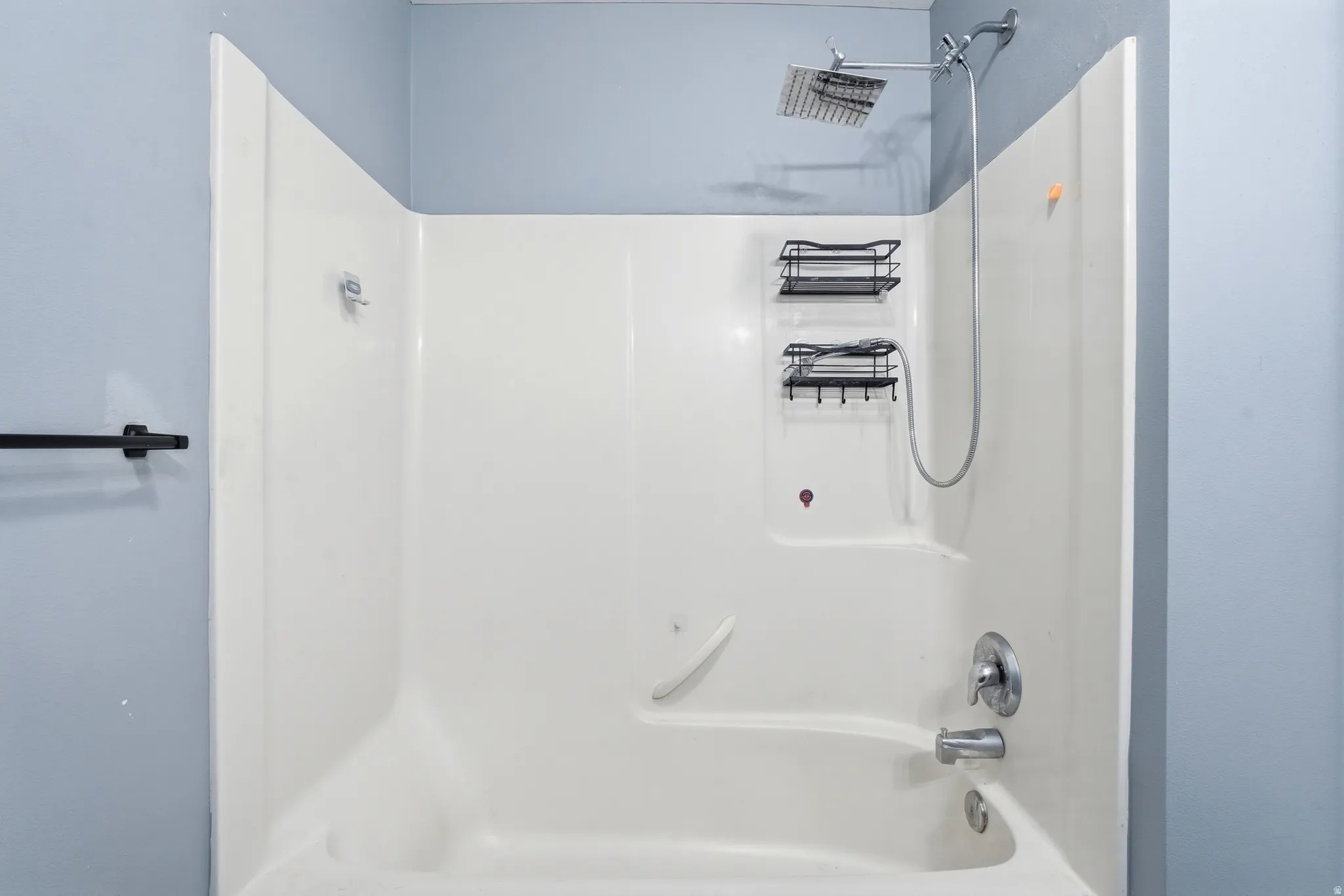 Bathtub and shower combination featuring a square rainfall showerhead, handheld shower fixture, and polished chrome hardware