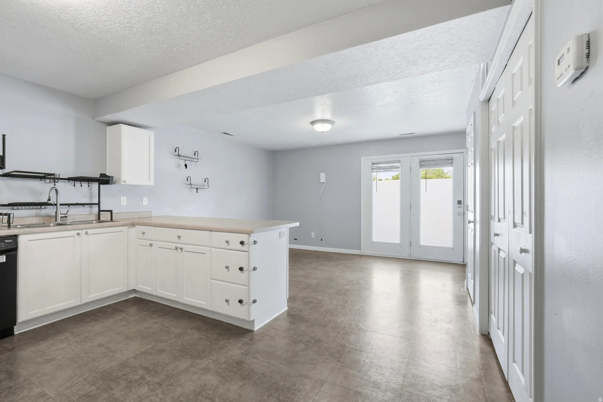 Kitchenette featuring white cabinetry, light countertops, and a stainless steel sink with a black faucet