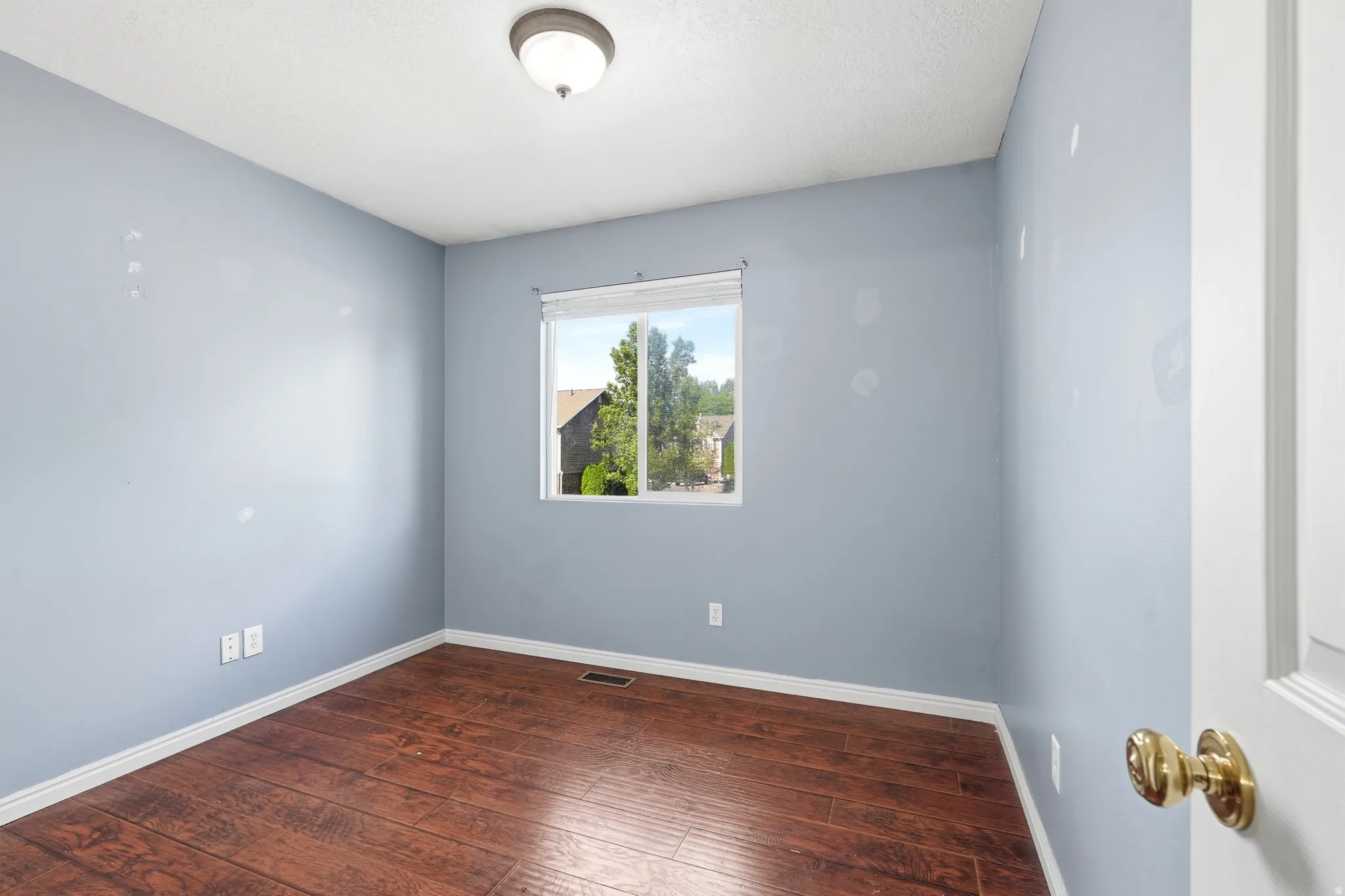 Bedroom featuring wood-finish flooring, a single window, and a ceiling-mounted light fixture