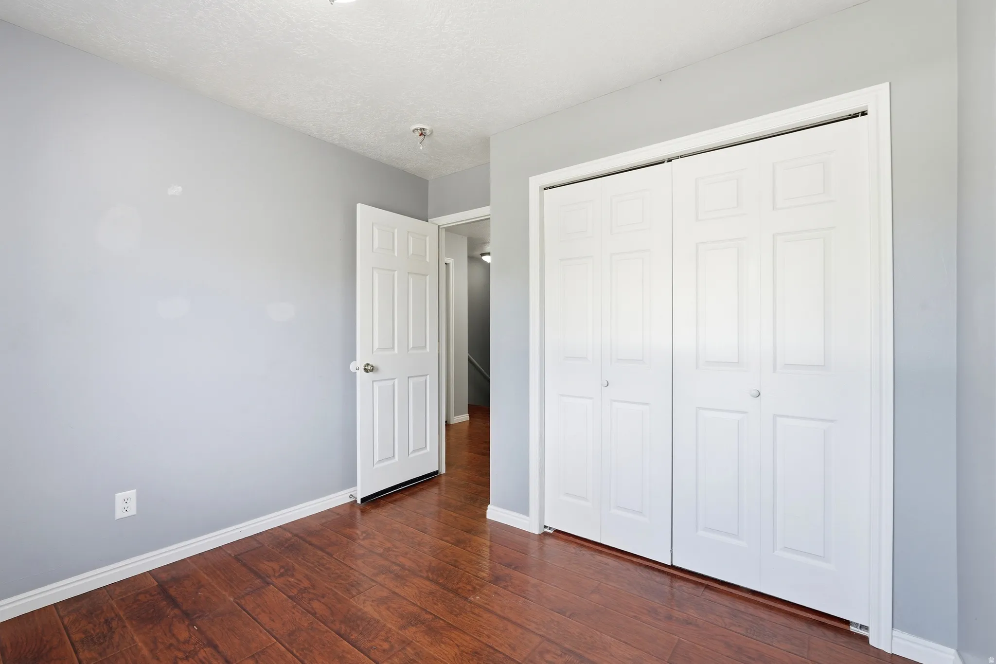 Interior room featuring wood-finish flooring, light gray wall paint, and white trim