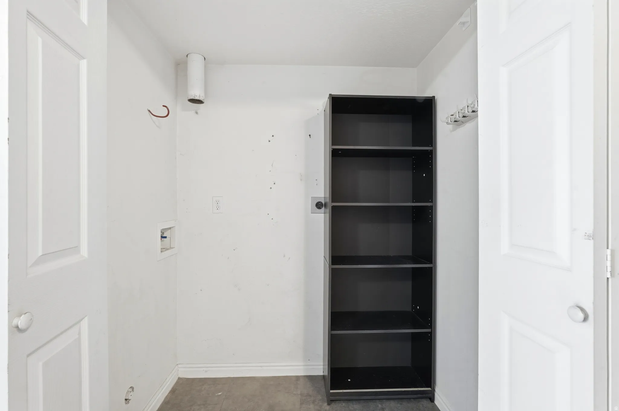 Utility area featuring a built-in shelving unit, white panel doors, and essential hookups for appliances