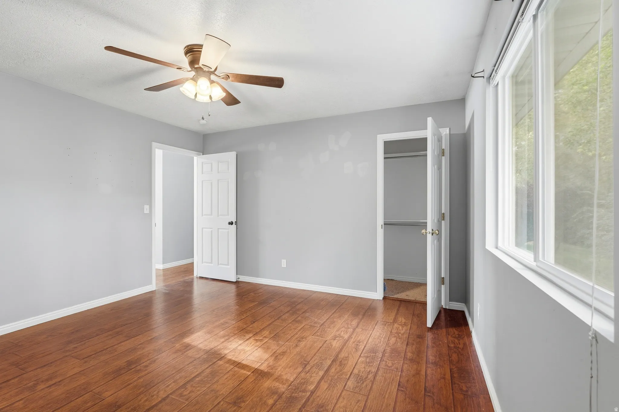 Spacious room featuring rich wood-finish flooring, light gray walls, and white trim