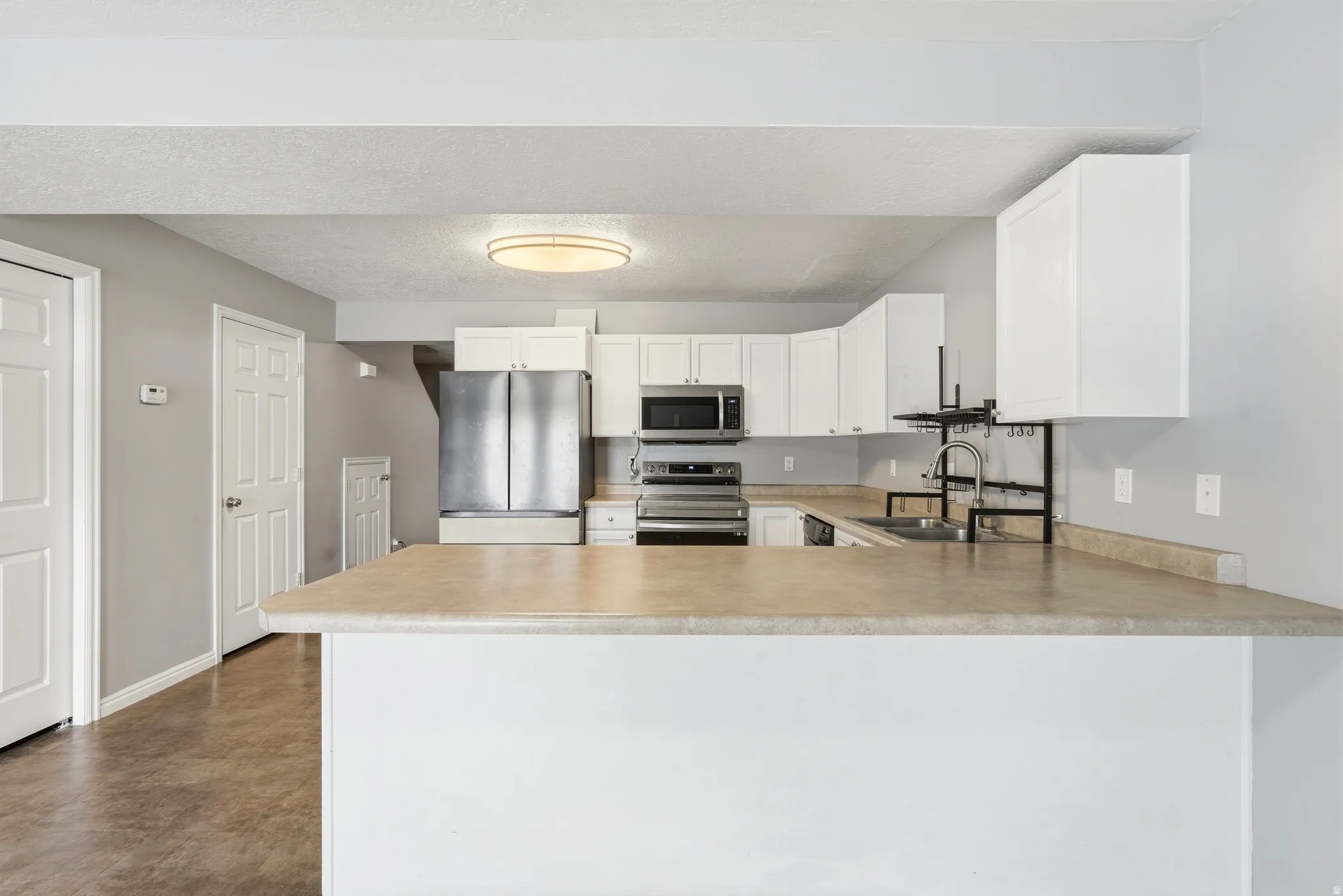 Kitchen featuring white cabinetry, stainless steel appliances, and a breakfast bar with laminate countertops