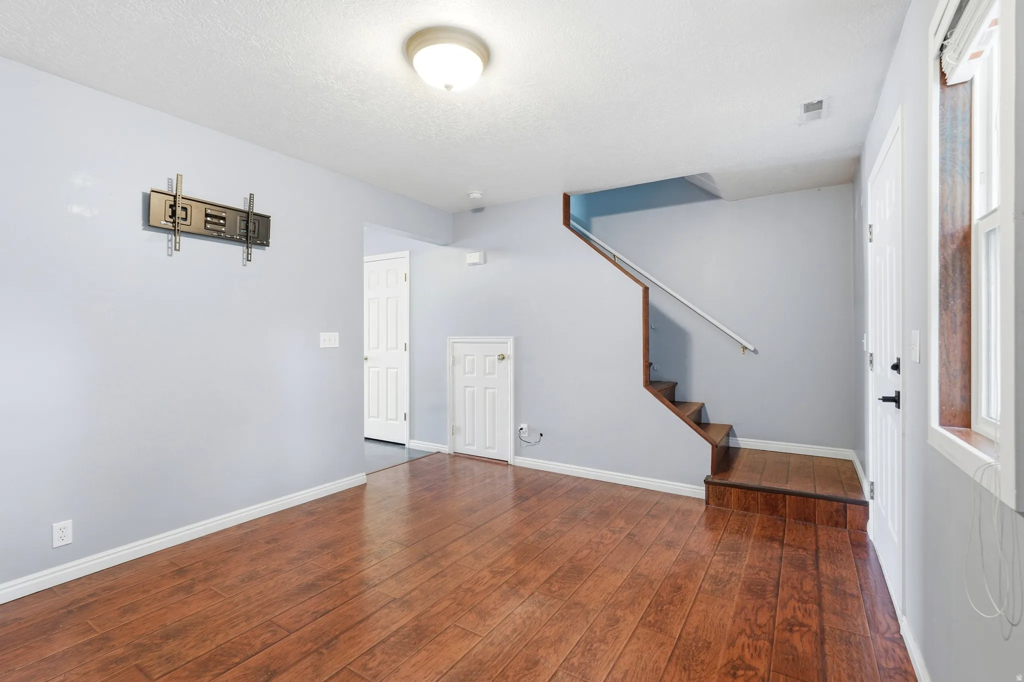 Spacious interior featuring wood-finish flooring, a built-in staircase, and light gray wall tones