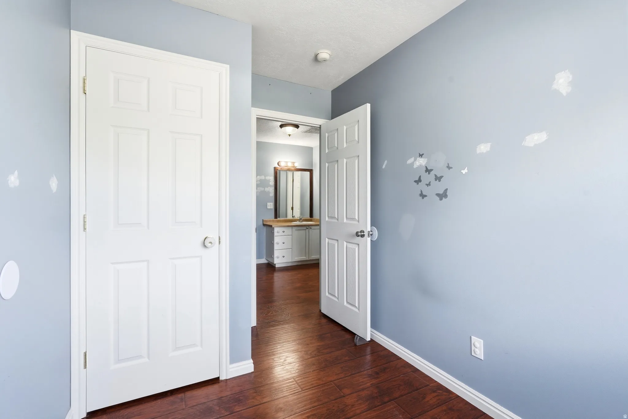 Wood-finish flooring extending from the foreground into an adjacent space, featuring a white paneled door