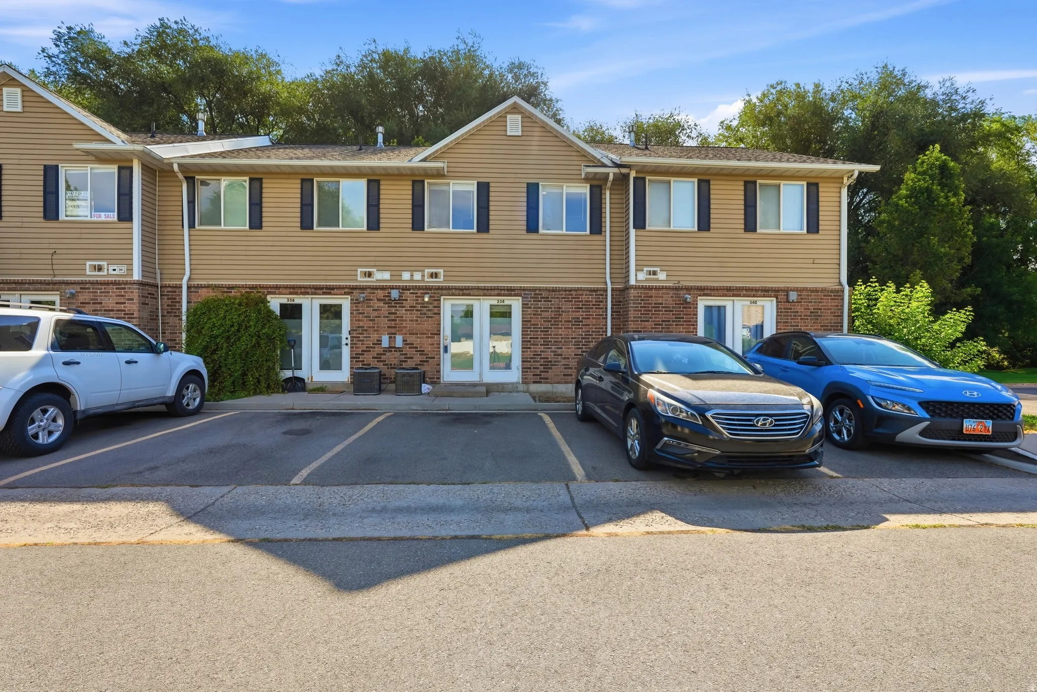 Multi-story residential building featuring tan siding and brick accents