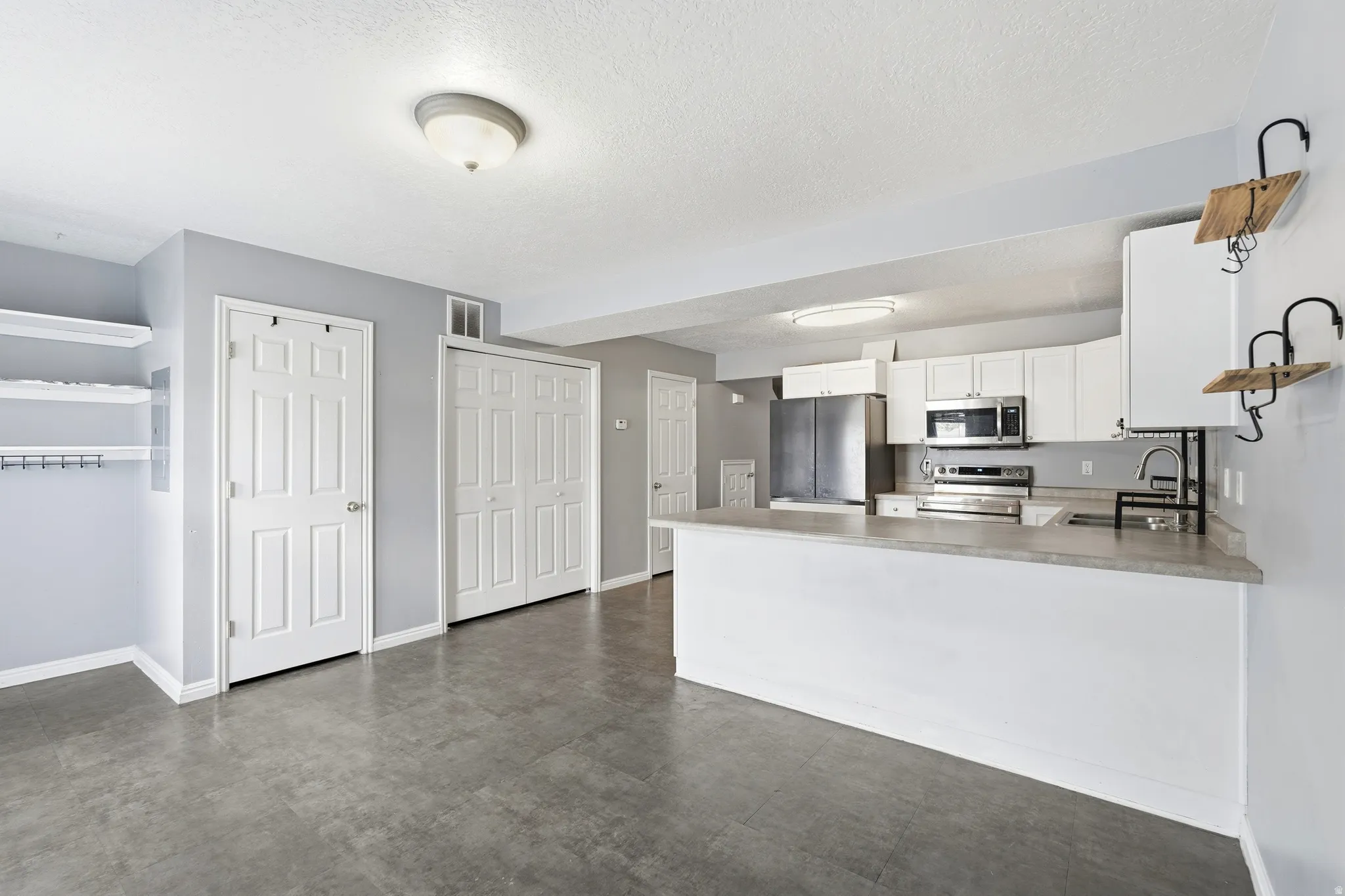 Modern kitchen featuring white cabinetry, stainless steel appliances, and an eat-at counter
