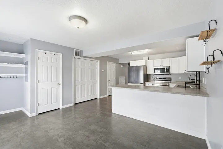 Modern kitchen featuring white cabinetry, stainless steel appliances, and an eat-at counter