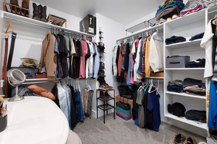 Walk-in closet featuring built-in shelving, multiple hanging rods, and light gray carpet