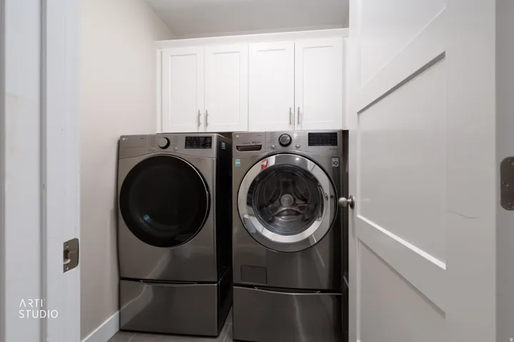 Laundry area featuring white shaker-style cabinetry, a contrasting light gray wall color, and a modern white interior door with paneling
