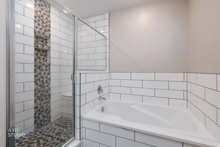 Shower enclosure featuring a mosaic tile accent wall, built-in shelving, and an integrated bench