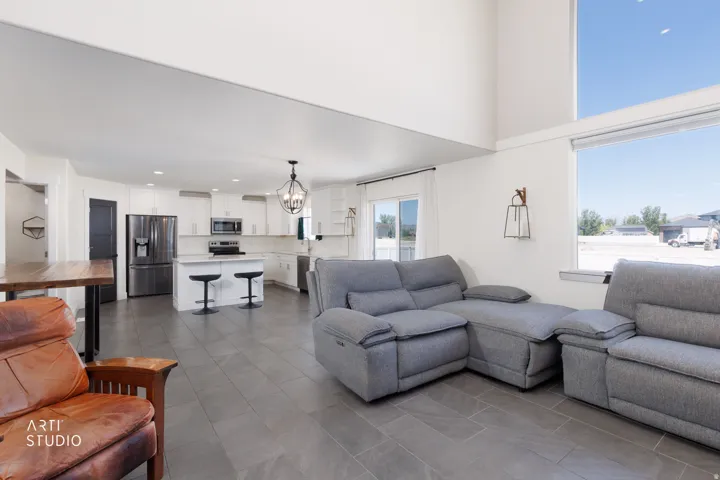 Open-concept living area featuring a kitchen island with seating, stainless steel appliances, a sliding glass door, and large windows