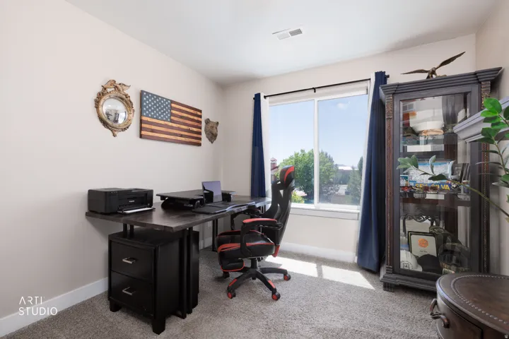 Bright interior space featuring a large window, light-toned walls, and neutral carpeting