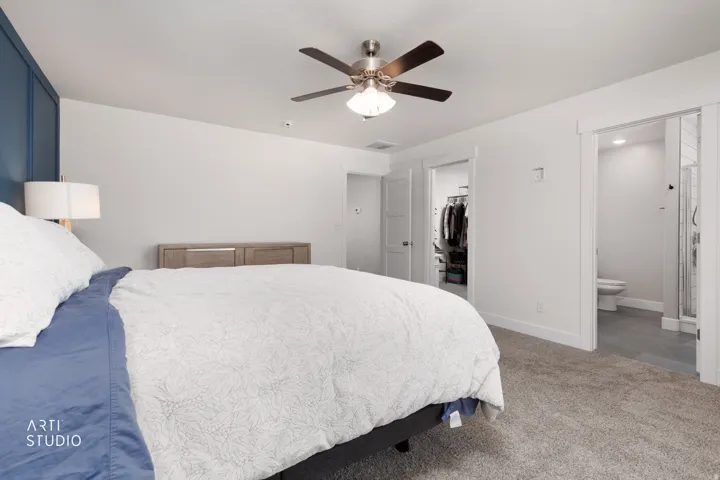 Bedroom featuring a paneled accent wall, neutral carpeting, and a ceiling fan with light fixture