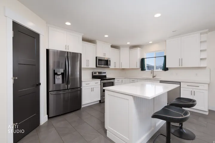 Contemporary kitchen featuring white cabinetry, stainless steel appliances, a center island with countertop seating, and recessed lighting