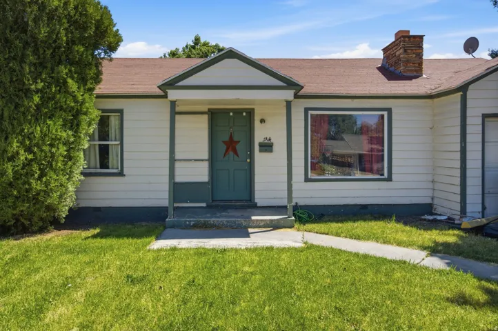 Single-story exterior with a covered entry, white siding, and dark green trim accents
