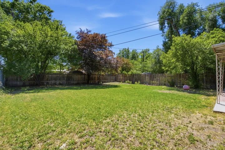 Expansive grass lawn with mature trees and a wood fence border