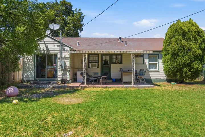 Rear exterior with horizontal siding, covered patio, sliding glass door, and a partially fenced perimeter
