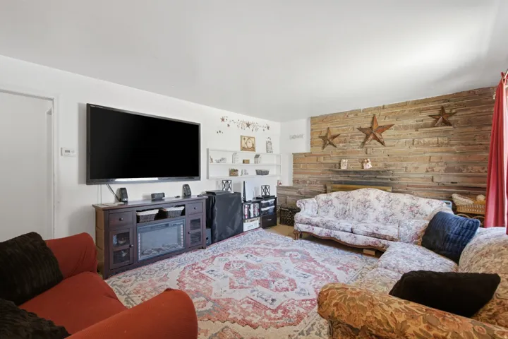 Living area featuring a stone accent wall with a fireplace, white shelving, and light-colored walls