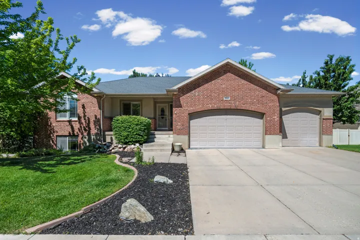Brick exterior residence with a dual garage featuring arched openings, a concrete driveway, and a landscaped front yard