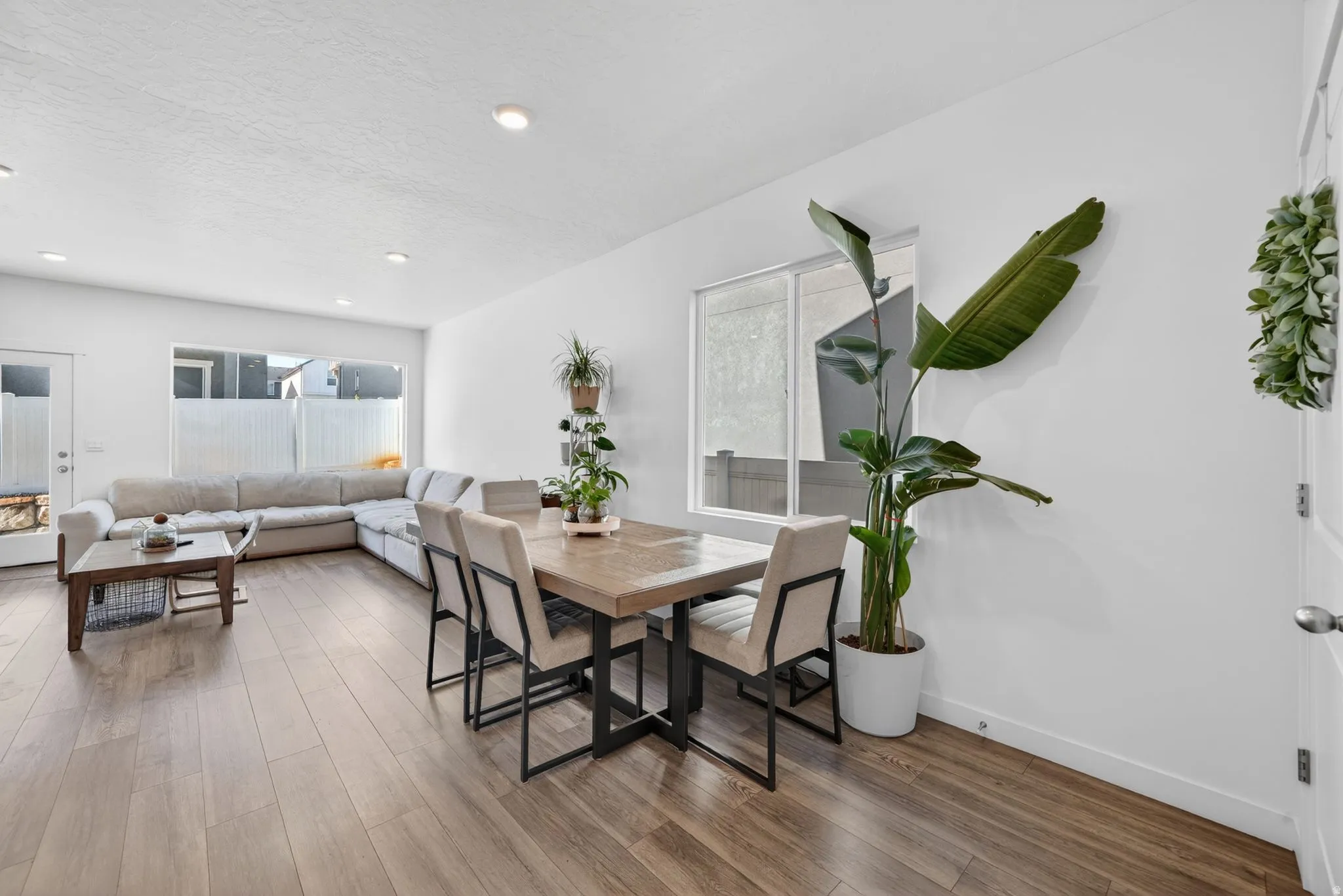 Open-concept living area featuring wood-finish flooring throughout, recessed lighting, and white baseboards