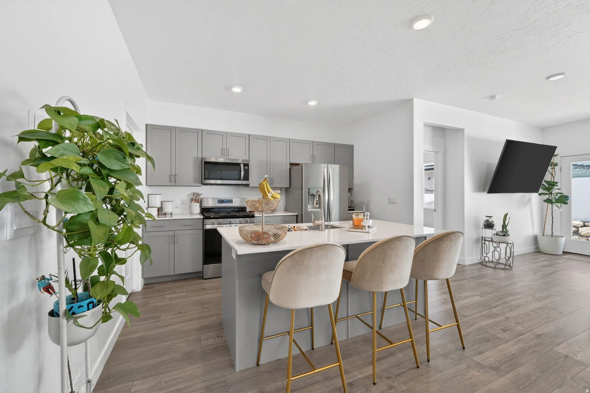 Modern kitchen featuring gray cabinetry, stainless steel appliances, a center island with countertop seating, and light wood-finish flooring