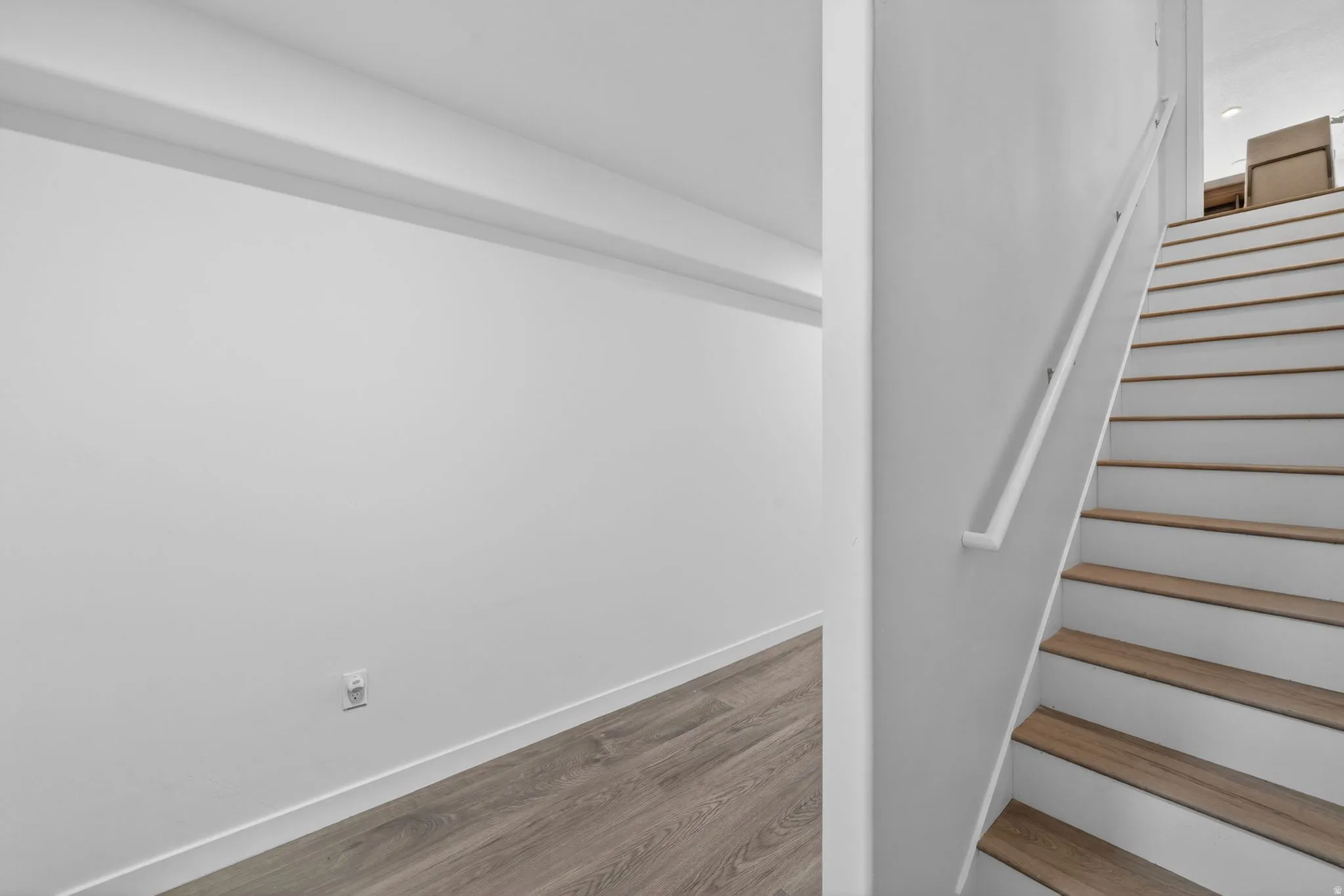 Staircase featuring wood-finish treads and risers with a white handrail